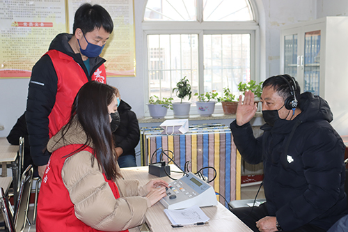 图为志愿者为社区居民进行听力检查